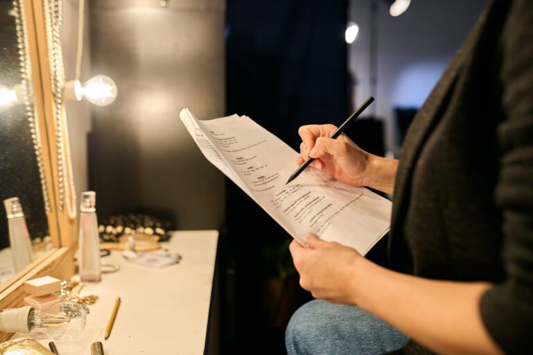 An actress is reading and analyzing a script in her dressing room, in front of the makeup mirror.