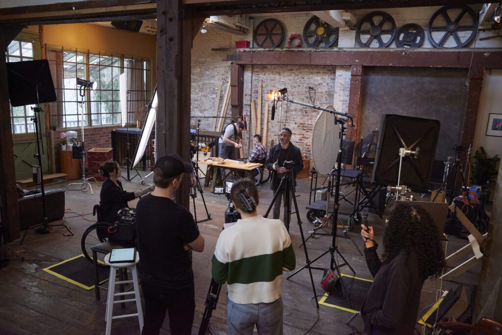 Behind the scenes footage of a commercial with disables actors being filmed in a brick studio.