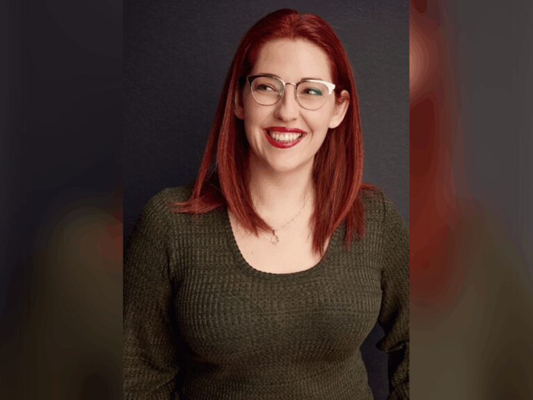 Casting Director Jessica Sherman smiling in front of a gray wall with a green shirt.