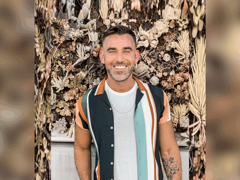 'Survivor' Casting director Jesse Tannenbaum in an open black, peach, orange, green and white shirt smiling outside near a floral arrangement.