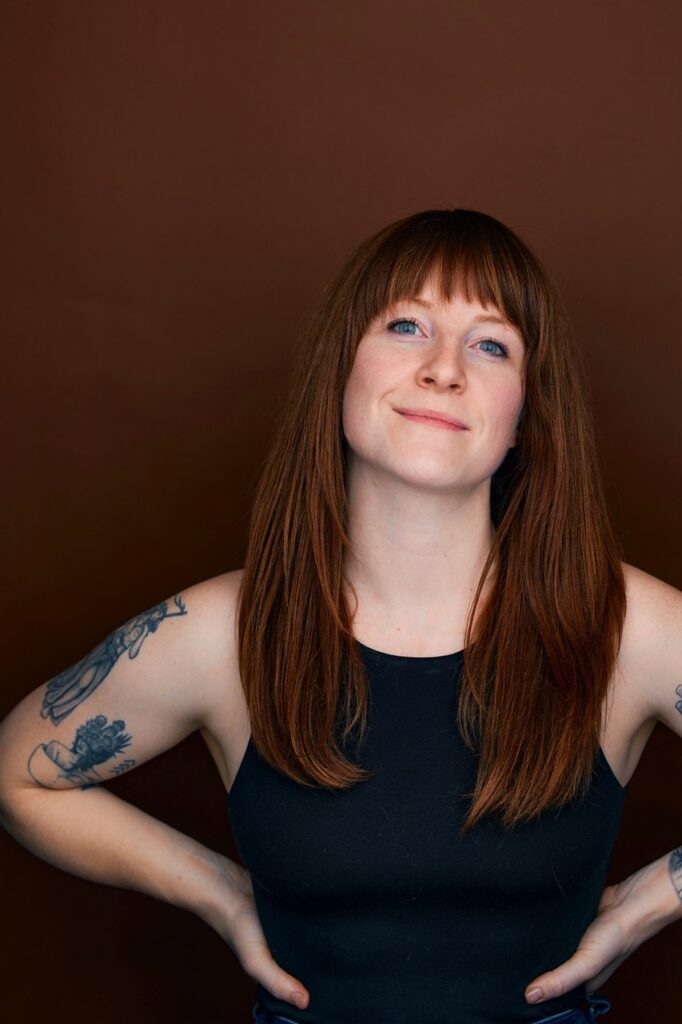 Casting Director Sarah Cayce smiling and looking confident in front of an auburn backdrop.
