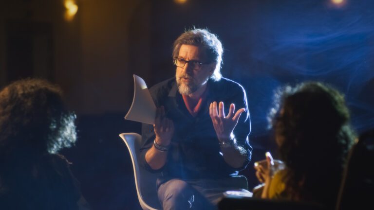 Theater director on a dim theater stage talking to the actors.