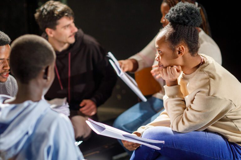 Diverse group of actors reading the script of a play together.