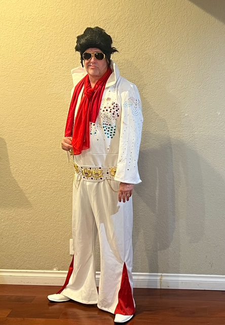 Mike Knox in a white Elvis Presley costume, complete with wig and red scarf.