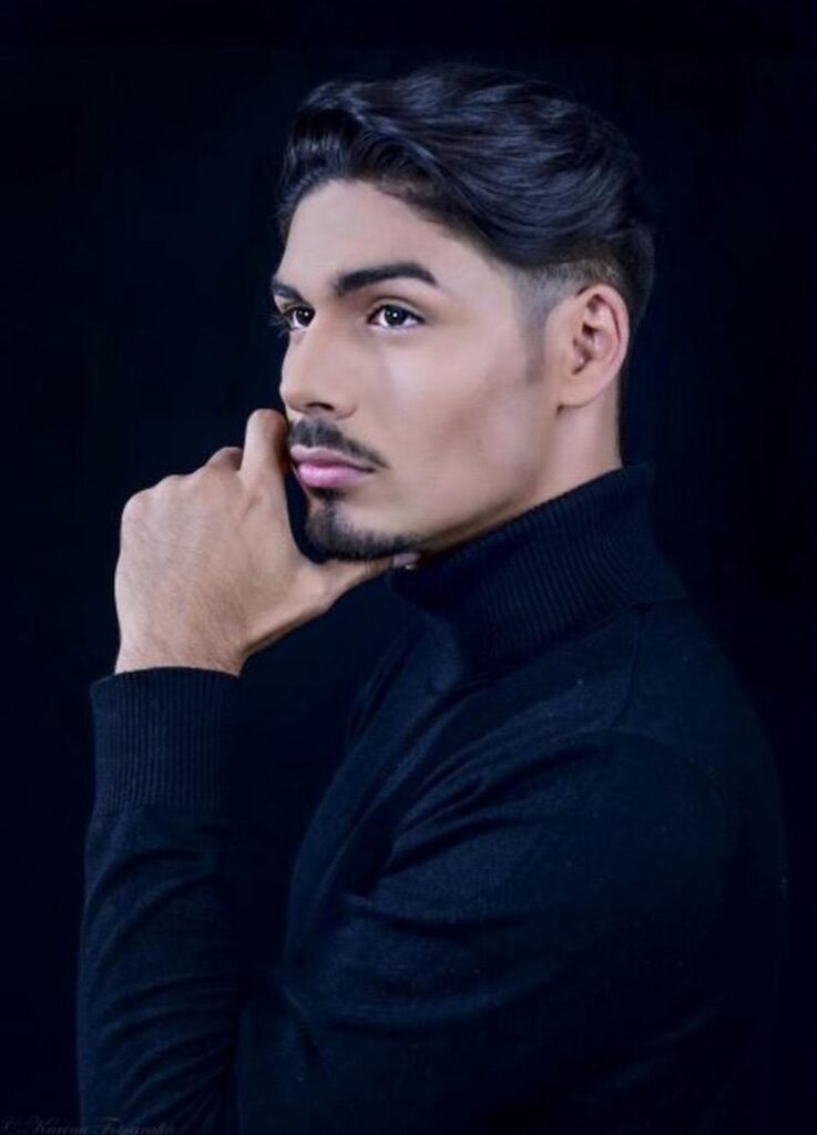 Actor Kerin Castillo in a nice black shirt hand on his chin looking stoic.