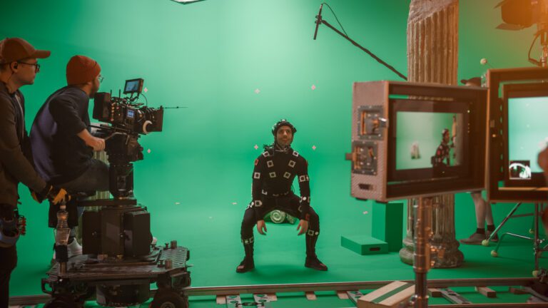 Film crew and director recording a motion capture actor on a green screen stage.