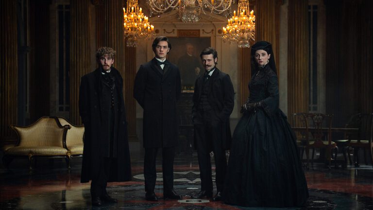 The cast of House of Guinness, dressed in black, Victorian outfits in a mansion in front of a painting.